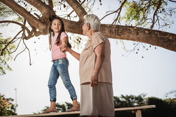 Grandmother playing with her granddaughter outdoors.