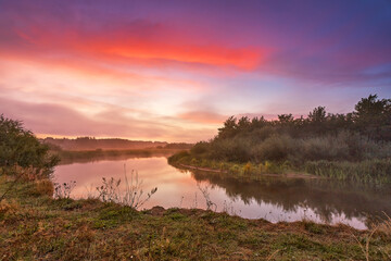 Fototapeta na wymiar River misty autumn sunrise. Colorful dawn. Cloudy sunrise. Dusk fall colors