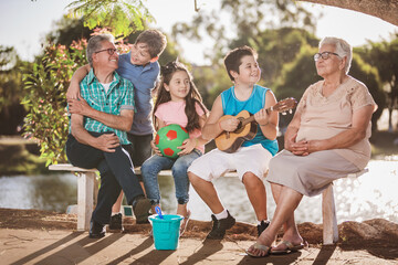 Grandparents and grandchildren playing on a bench in a park