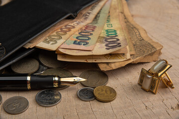 Old coins, fountain pen, wallet, cufflinks and more on a rustic wooden surface, selective focus.