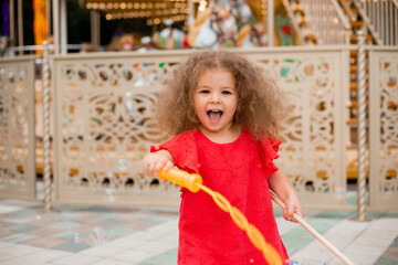 Little curly girl lets bubbles and rejoices