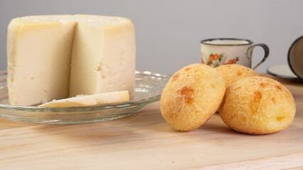 Minas cheese, cup of coffee and cheese bread from Brazil, arranged on a table with beige tablecloth and gray fudo, selective focus.