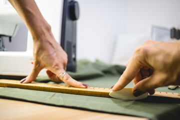 Selective focus of seamstress marking cloth with soap and ruler on table in workshop 