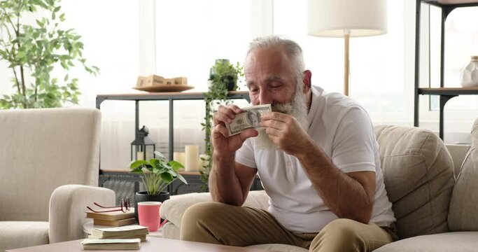 Senior man verifying and checking american dollar bills for authenticity and detection of counterfeit money
