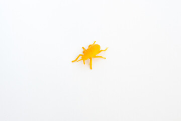 plastic toy insect - orange beetle or tick on the white background, isolated, close up
