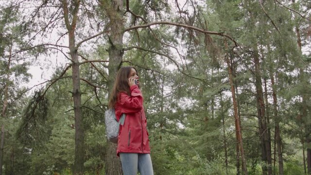 Young caucasian woman in a coronavirus mask talking on a smartphone in the autumn forest.
