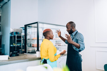 Ethnic adult displeased employees disputing while working in cafe