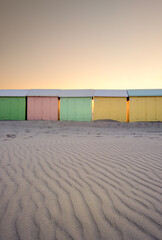 Pastel colored beach huts against sunset sky in Berck (France)