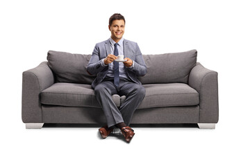 Young man sitting on a sofa with a cup of coffee