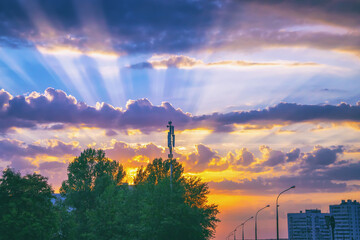 Dramatic sunset with sun rays and clouds in the city