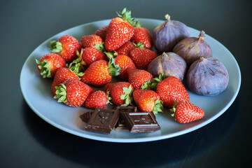 fresh strawberries and figs on a plate with chocolate pieces