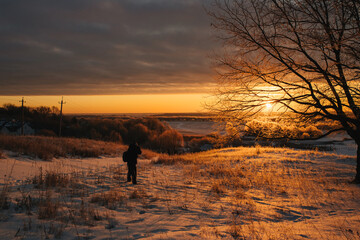 silhouette of a man walking in the snow at sunset