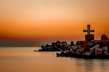 Sunrise over a sea beach with Christian cross