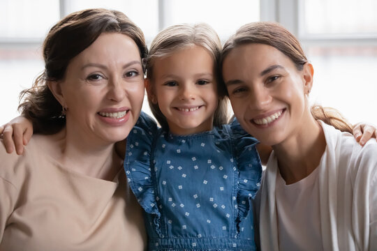 Portrait Of Bonding Mixed Race Multigenerational Female Family. Happy Little Preschool Adorable Kid Girl Cuddling Biracial Mother And Beautiful Mature Senior Granny At Home, Looking At Camera.