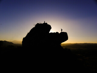 piedra encima de montaña con sujeto en el atardecer
