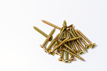 Gold screws scattered randomly on a white background. Yellow zinc head screws