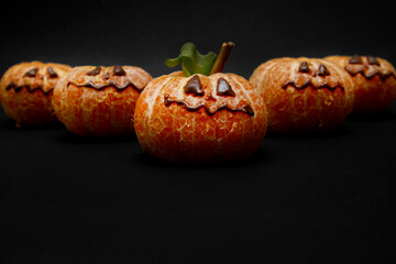 Halloween face on the peeled whole tangerine or mandarine orange fruits. Halloween minimal concept.