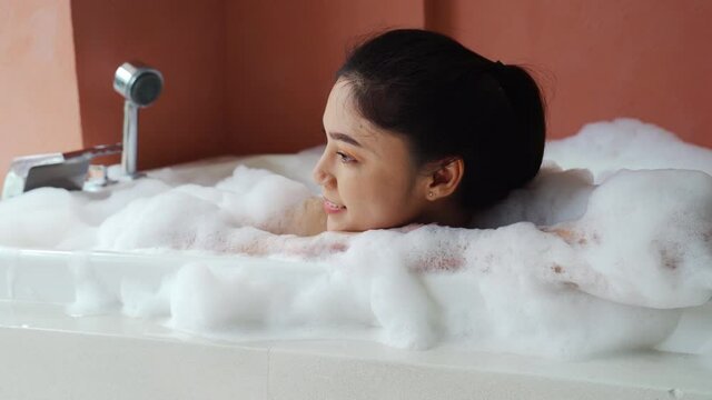 young woman relaxing and takes bubble bath in bathtub with foam