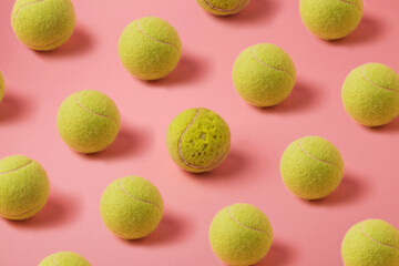 Old tennis balls arranged on pink background, creative colorful pattern with worn out tennis balls