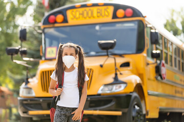 Back to school. Schoolgirl wearing medical face mask to health protection from influenza virus. Child going school after pandemic over.Portrait of a schoolgirl on the background of the school
