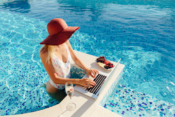 sexy woman using laptop and work remotely near swimming pool. Sexy female blogger browsing laptop online home pool outdoors. Champagne drinking on summer vacations. Online female entrepreneur.