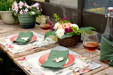 Outdoor cafe restaurant setting for warm summer evening romantic dinner dates in sheltered patio with beautiful table decor and wine
