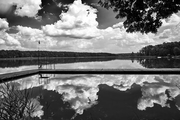 Wooden pier and reflection of clouds in the waters of Lake Chycina