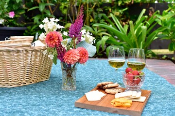 Outdoor summer gourmet picnic basket foods in beautiful romantic garden setting for special...
