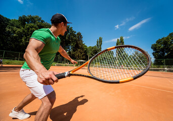 Young athletic man playing tennis on the court.
