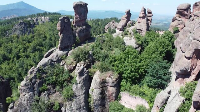 Aerial tilt up shot above cliff showing beautiful rocky mountains surrounded by forests - Belogradchik Bulgaria