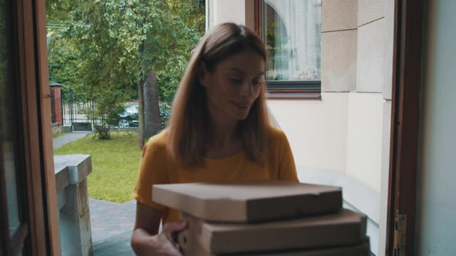 Caucasian woman receiving fast food pizza order delivery during coronavirus pandemic. Courier wearing face mask for social distancing. Health care. Delivery services.
