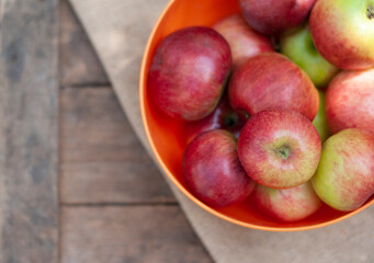 red apples in the orange plate on the wood box