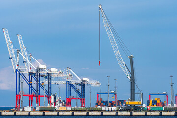 The infrastructure of the commercial port. Cranes for loading and unloading operations in the port. Loading of ships and railway cars. Transport terminal. Different types of cargo transportation.