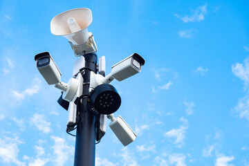 Close-up of outdoor surveillance cameras, floodlights and loudspeakers on a street pole. Ensuring...