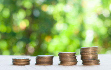 stack of coins on the table in the nature blurred background with bokeh lights