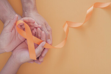 Adult and child hands holding orange Ribbons,  Leukemia cancer and Multiple sclerosis, COPD and ADHD awareness, world kidney day