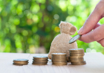bag of money, stack of coins and hand with coin on the nature blurred background with bokeh lights