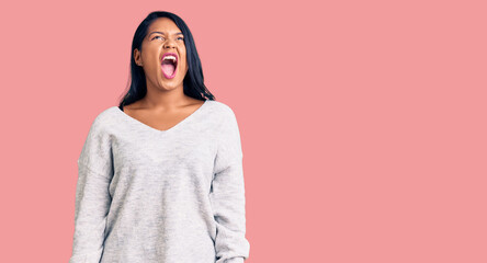 Fototapeta premium Hispanic woman with long hair wearing casual clothes angry and mad screaming frustrated and furious, shouting with anger. rage and aggressive concept.