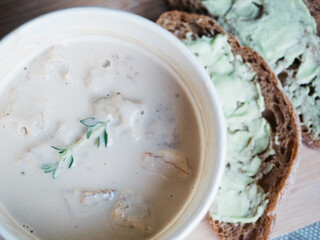 Creamy mushroom soup in cardboard cup served with bread with green color butter