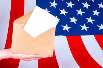 Fototapeta na wymiar Envelope and stamps paper on the background of the American flag. Correspondence with US government agencies. Voting in the election of the President of the United States. Letter to American friends.