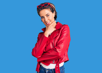 Young beautiful woman wearing red leather jacket looking confident at the camera smiling with...