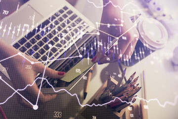 Double exposure of businesswoman hands typing on computer and financial graph hologram drawing. Stock market analysis concept.