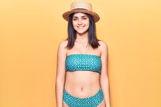 Young beautiful girl wearing bikini and summer hat with a happy and cool smile on face. lucky person.