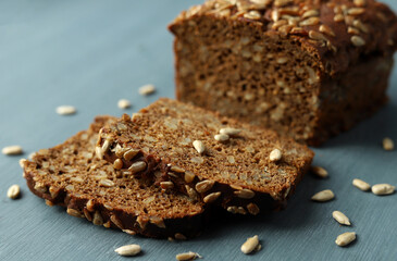 Fresh black bread with sunflower seeds cut into pieces on a dark wooden background. Selective focus.