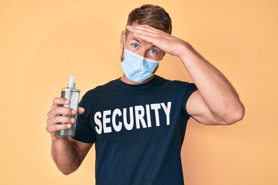 Young caucasian man wearing security t shirt and medical mask holding hand sanitizer gel stressed and frustrated with hand on head, surprised and angry face