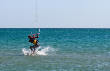 a kitesurfer surfing on the smooth azure water. recreational sport. A Man Rides A Kiteboarding In The Sea Water. extreme sport. Jump