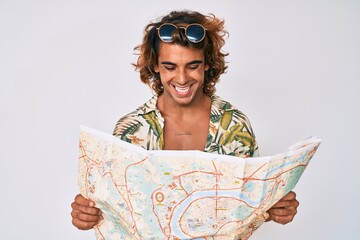 Young hispanic man wearing summer style holding map smiling and laughing hard out loud because funny crazy joke.