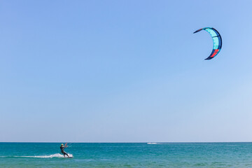 a kitesurfer surfing on the smooth azure water. recreational sport. A Man Rides A Kiteboarding In The Sea Water. extreme sport. Jump