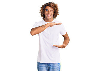 Young hispanic man wearing casual white tshirt gesturing with hands showing big and large size sign, measure symbol. smiling looking at the camera. measuring concept.