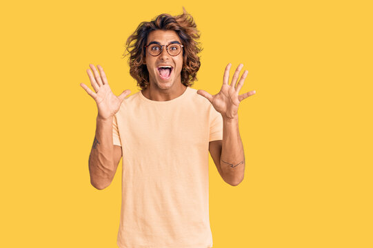 Young hispanic man wearing casual clothes and glasses celebrating crazy and amazed for success with arms raised and open eyes screaming excited. winner concept